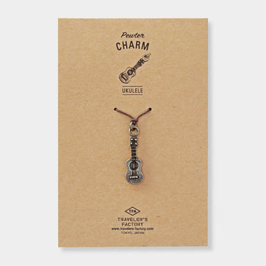 Ukulele-shaped charm on a brown card with 'Traveler's Factory' branding.