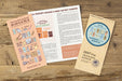 TRAVELER'S notebook Regular Size 2027 Weekly Calendar and Memo Diary showing stickers and notebook guide open on a table. 