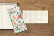 TRAVELER'S notebook 2027 Regular Plastic Sheet image showing both front,  and back of sheet with grid pattern and metric rule next to a TRAVELER'S notebook (not included.)