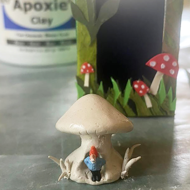 A Gnome's Mushroom Home class sample in progress with mushroom formed with apoxie clay  (unpainted) and small gnome.