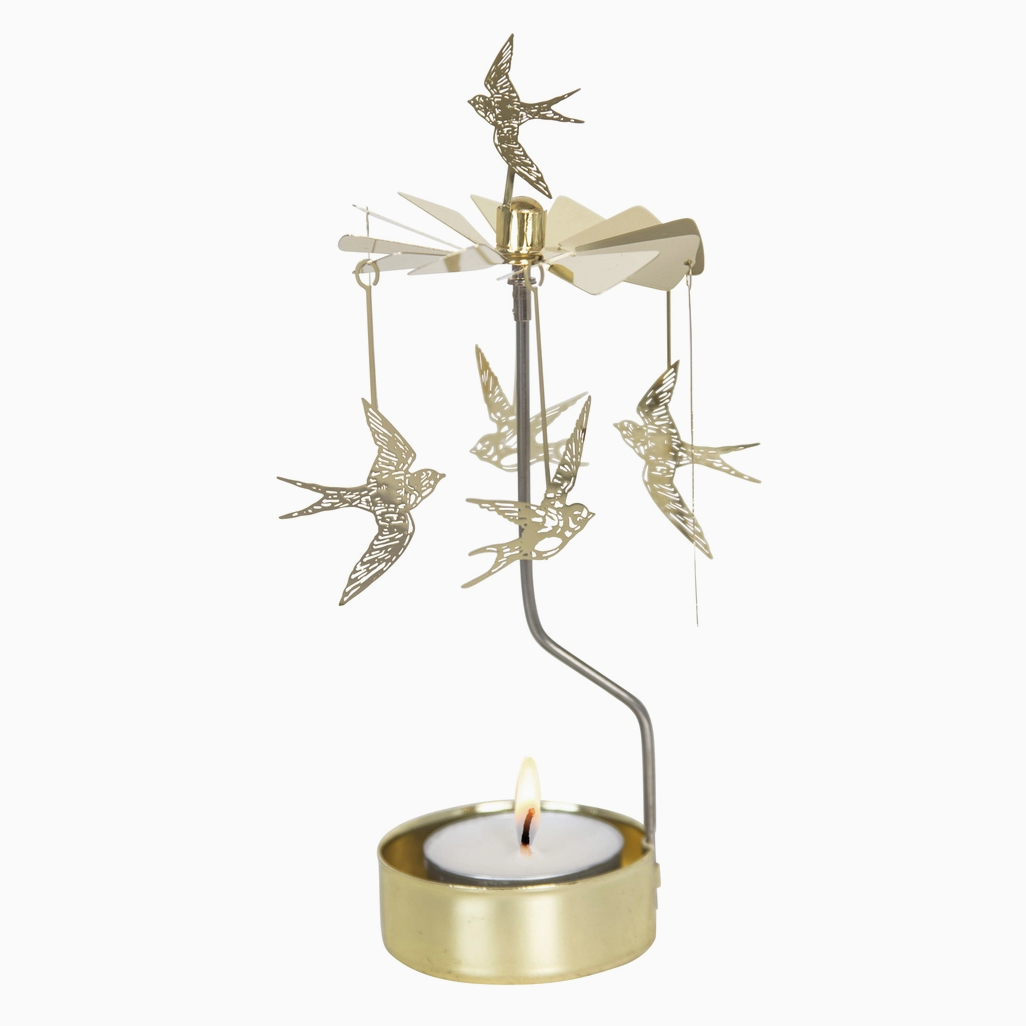 A gold-toned metal bird mobile candle holder with several hanging bird ornaments and a lit tealight candle in a round gold holder, shown against a plain white background.