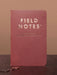 Red notebook with 'Field Notes' branding on a brown background