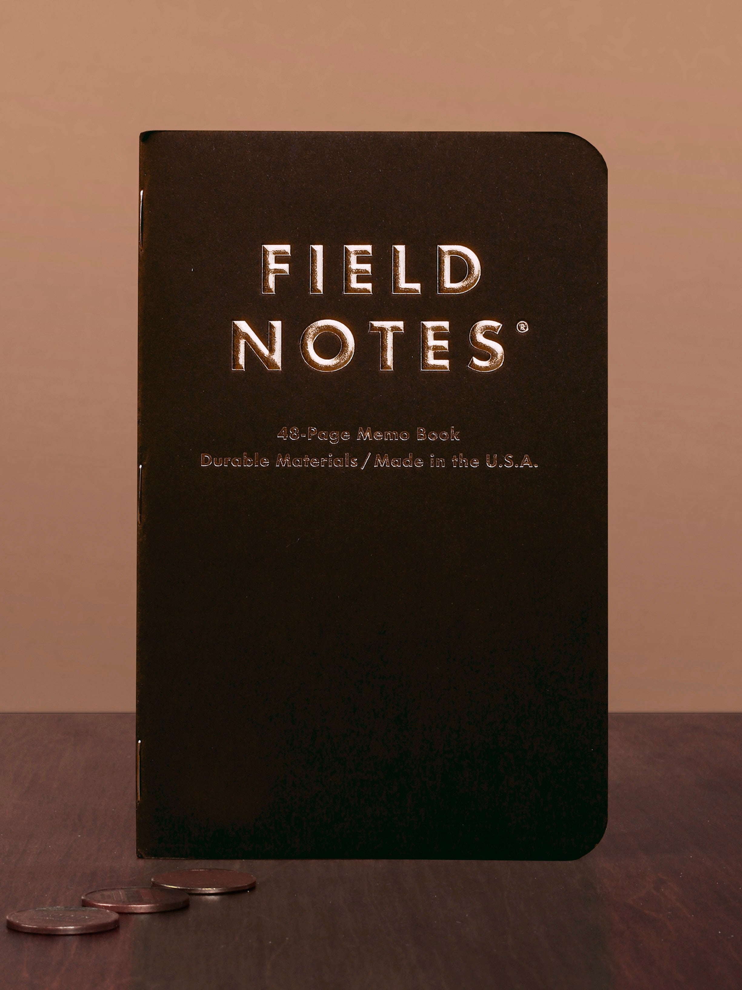 Black Field Notes notebook on a wooden surface with a brown background