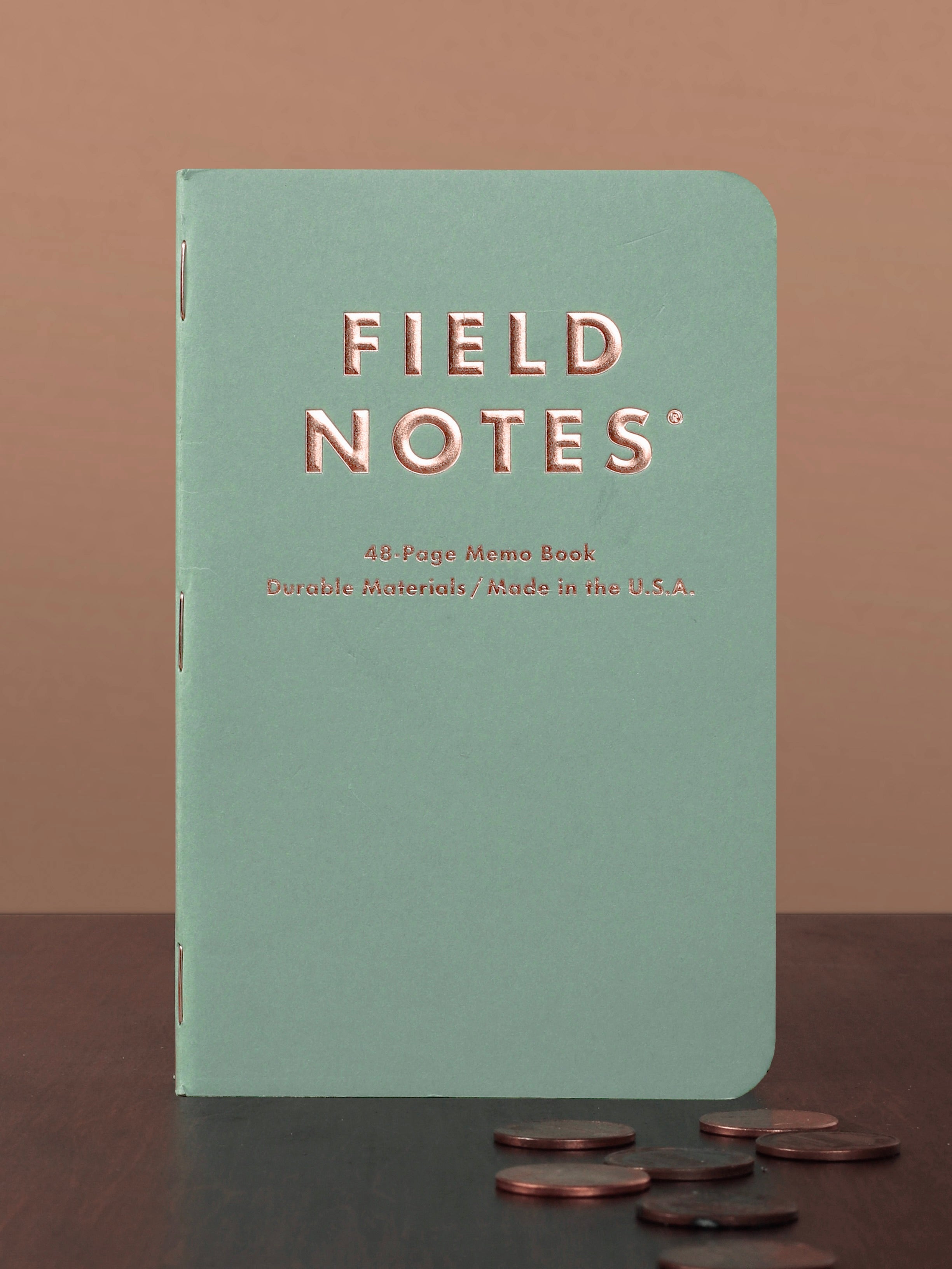 Field Notes notebook on a brown surface with coins