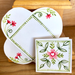 Card and  open envelope with red and green floral design on a wooden surface