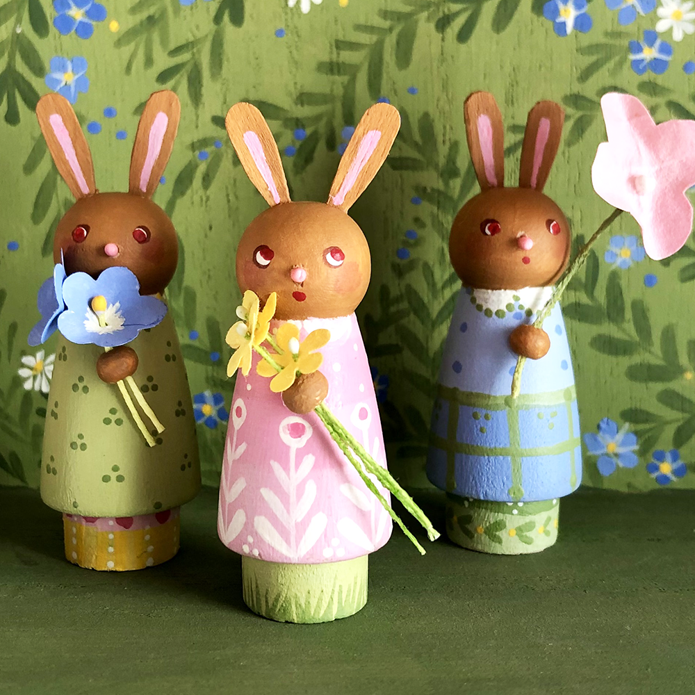 Wee Bunnies Three!  class samples- three peg doll bunnies holding flowers with painted background