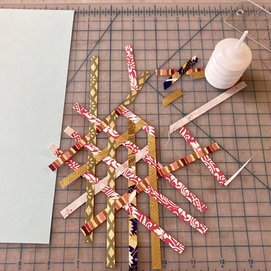 Woven hexagon geometric paper design on a cutting mat background with glue- work in progress
