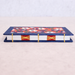 A small decorative book with a navy blue cover, a colorful floral pattern on the top, white pages, and gold thread binding, photographed on a light beige surface against a pale gray background.