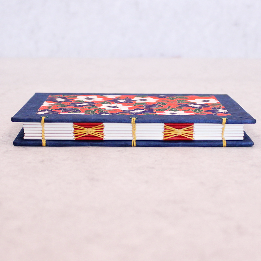 Book with floral design on cover and decorative spine stitch on light gray background