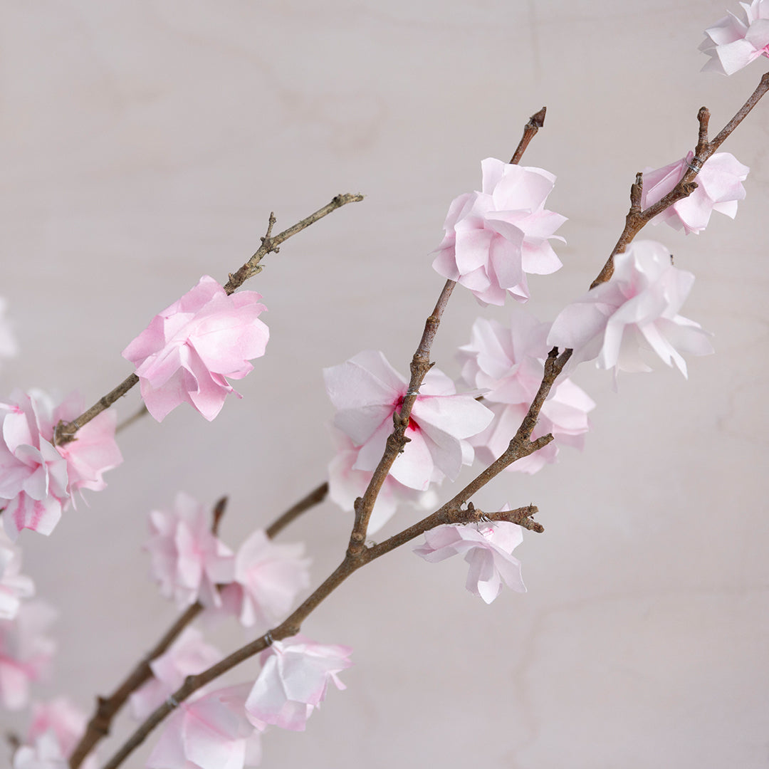 Paper cherry blossoms attached to branches- detail