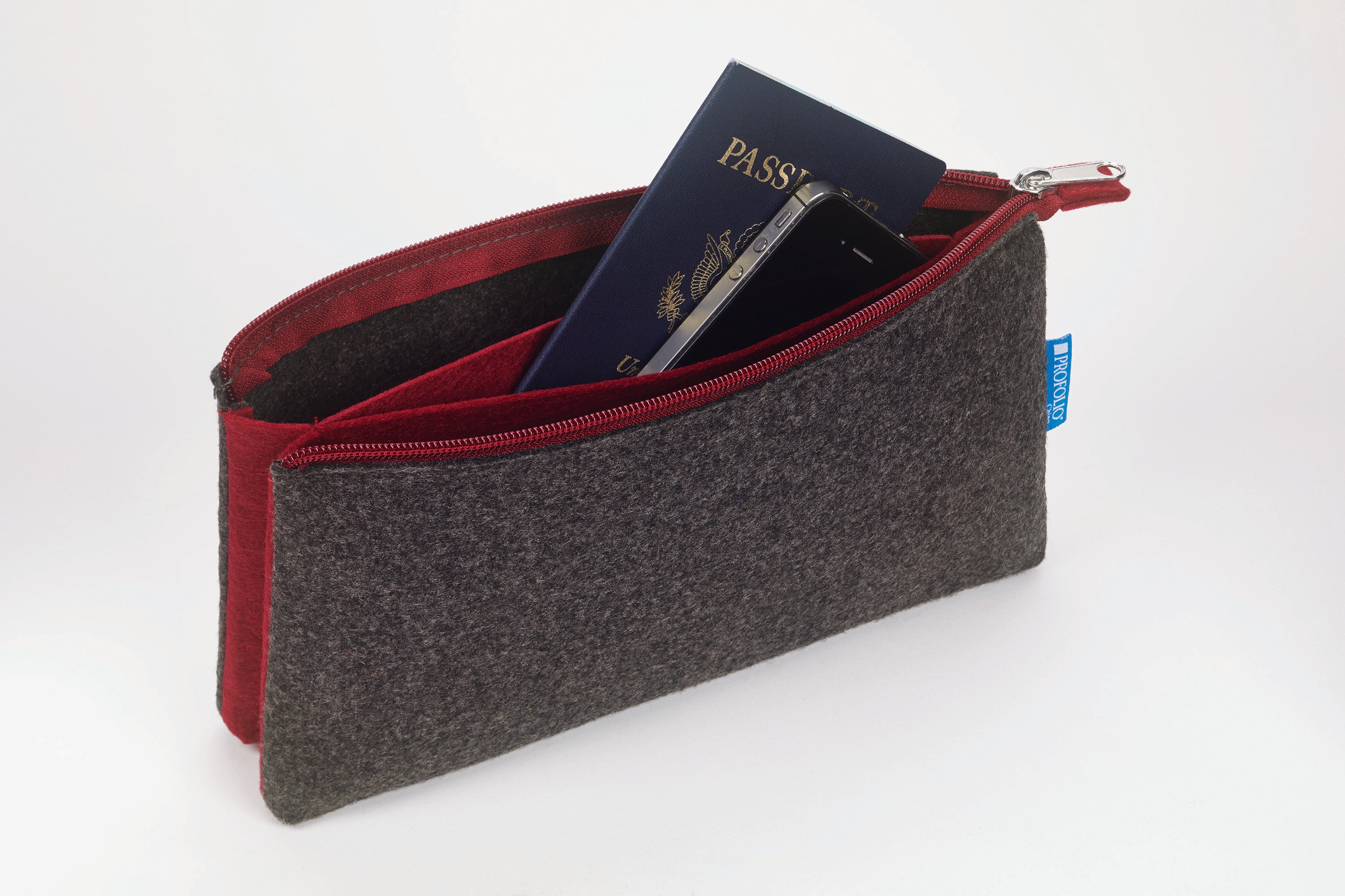 A dark gray felt zippered pouch with a red interior lining, shown open with a blue passport and smartphone inside. 