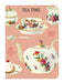 Mini notebook with decorative tea time design with teapots, teacups, and a cake on a pink background.