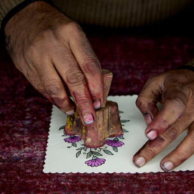 Artist hand stamping card with block print in hands