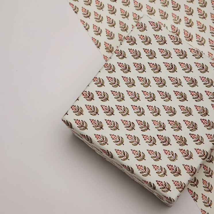 Sheet of paper with a repeat floral and leaf pattern with a wrapped ox in the same pattern shown on top.