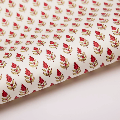 Paper with red and green floral and leaf repeat pattern on a white background