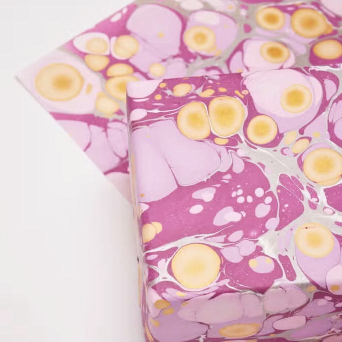 Handmade Indian Cotton Paper with circular patterns in shades of purple used as a gift wrapped package and shown with flat sheet