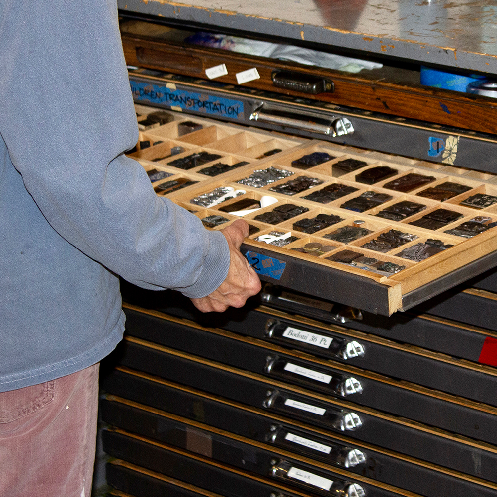 Person opening letterpress type tray drawer