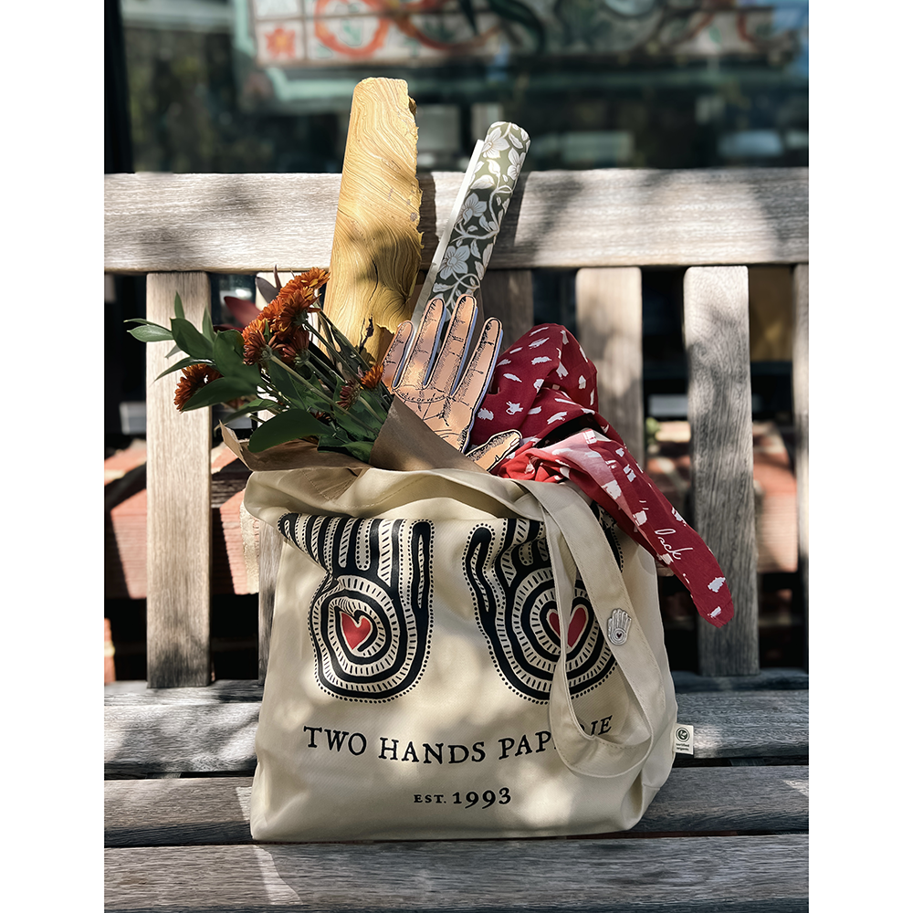 Two Hands Paperie totebag filled with store goodies sitting on bench