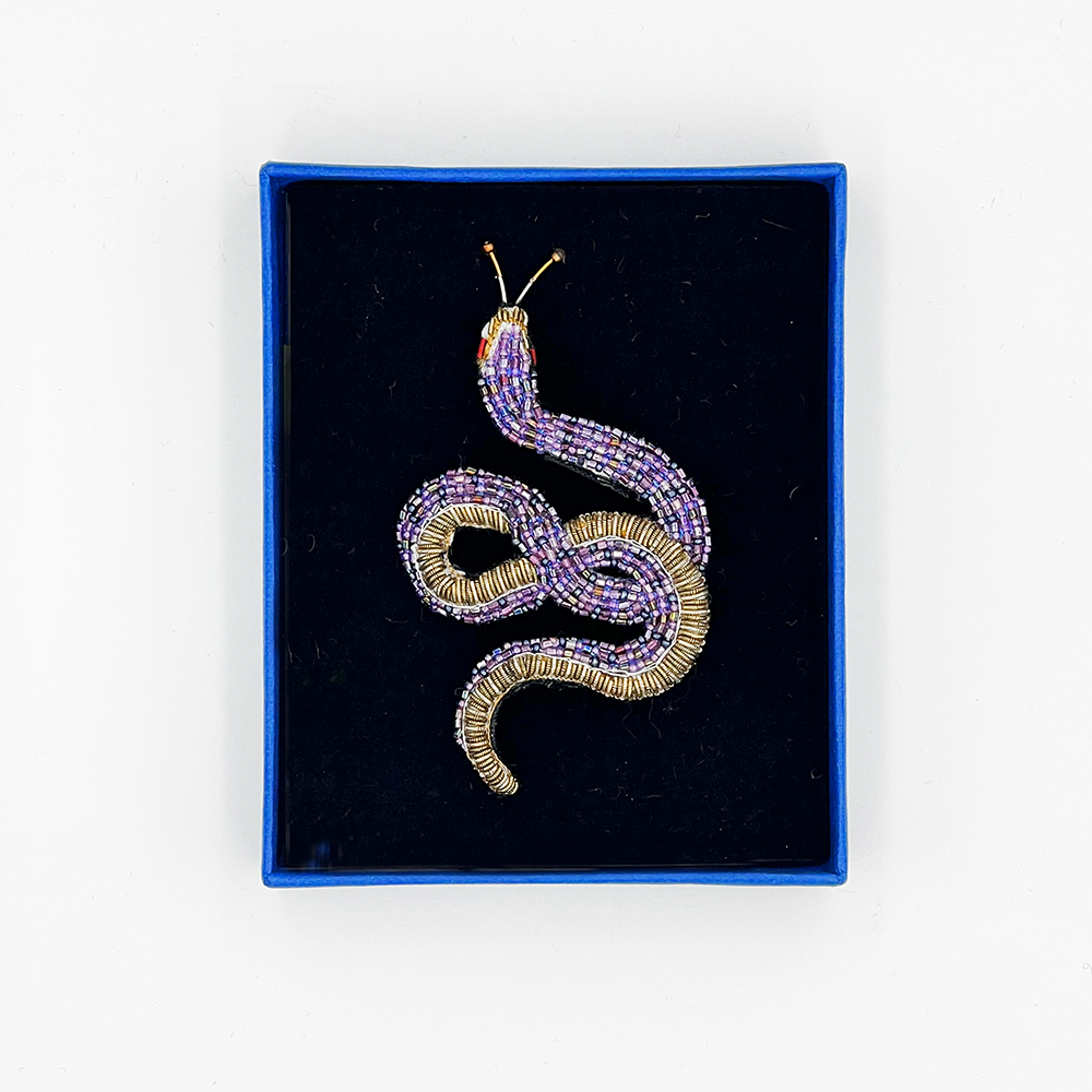 Beaded snake brooch in a blue box with black velvet lining on a white background