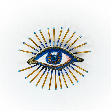 Decorative beaded brooch with an eye design on a white background