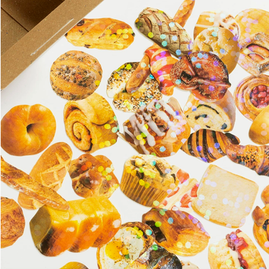 Assorted pastry stickers on a white surface with a cardboard box in the background