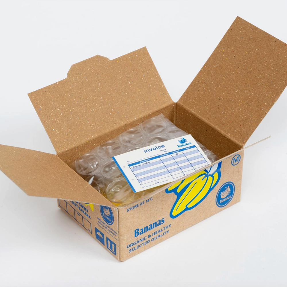 Open cardboard box with banana packaging and an invoice on a white background