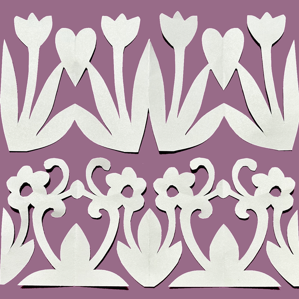 White paper cutout floral and scroll border designs arranged in two rows on a solid mauve-purple background.