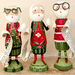 Three hand-painted wooden Christmas Santa Claus figurines standing on round bases, each holding a scroll, set against a plain beige background.