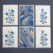 Set of six cards with floral designs and marbled patterns on a dark background