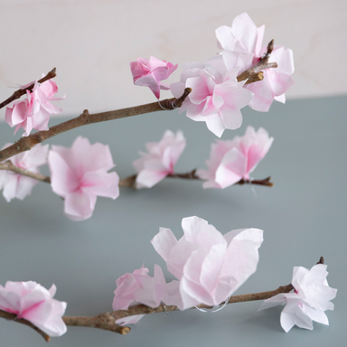 Branch with paper cherry blossom with pink flowers on a gray background