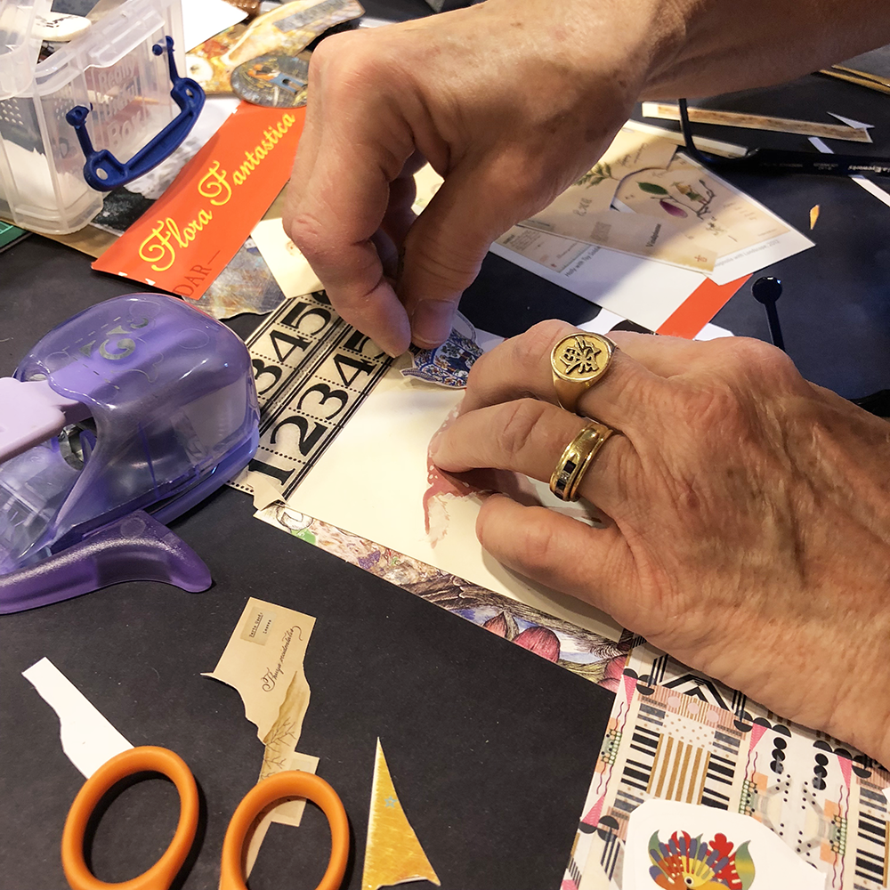 collage in progress with paper scraps and hands